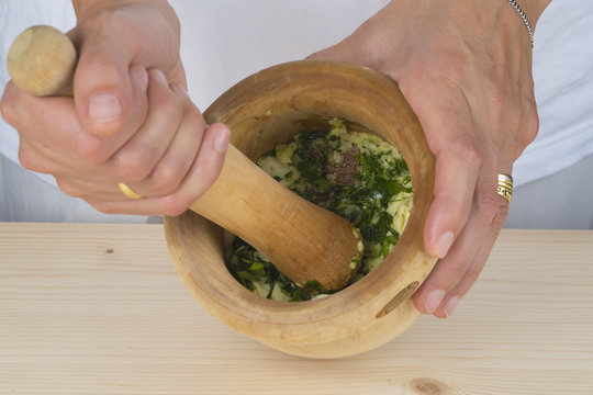 Cocinero preparando un majado de ajo y perejil en el mortero
