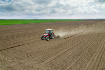 Farmer sowing crops at field with tractor