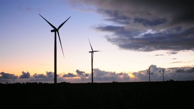 Wind turbines at sunset with clouds advancing