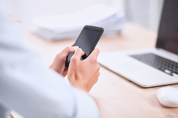 Businesswoman sending message with smartphone sitting in the