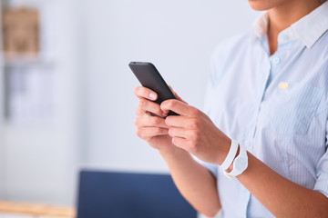Businesswoman sending message with smartphone sitting in the