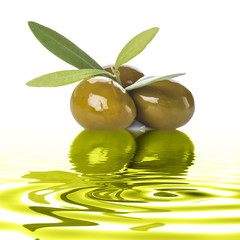 Aceitunas verdes con hojas reflejadas en aceite de oliva