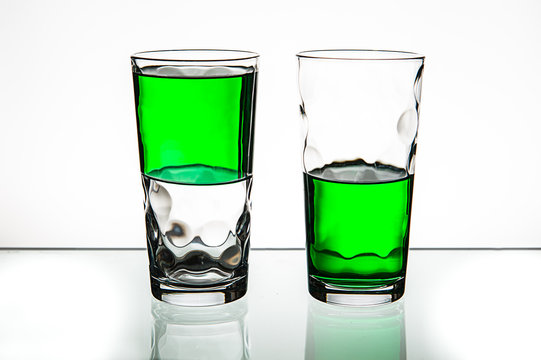 Two glasses, both half-full of green liquid.