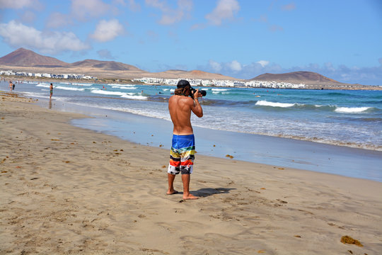 hombre fotografiando en la playa de famara de lanzarote