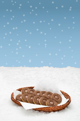 Basket with cookies standing in the snow.