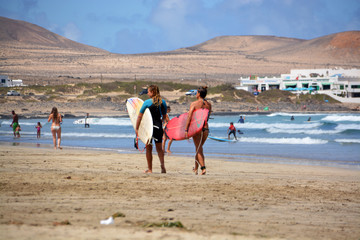 dos surfistas caminando por la playa