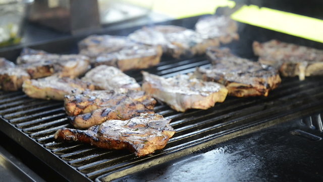 A man grills lamb chops on the outdoor barbecue