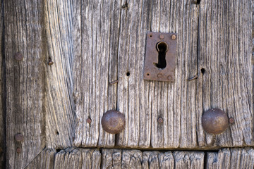 Front view of old lock and wooden door with iron nails
