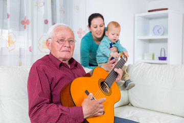 Grandfather playing the guitar to his grandson