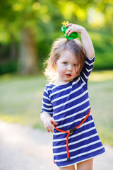 Beautiful little girl in red rain boots playing with rubber frog