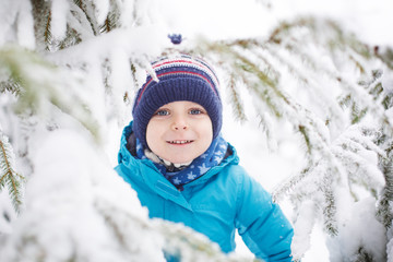 Fototapeta na wymiar Little toddler boy having fun with snow outdoors on beautiful wi