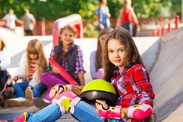 Girl holds helmet wearing in-line skates sitting
