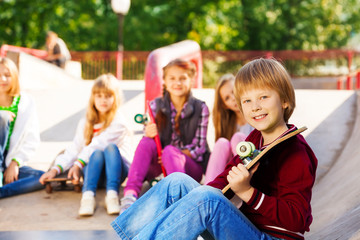 Boy with skateboard and his friends sitting behind