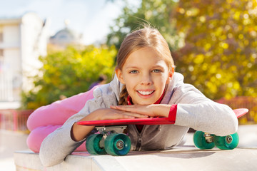 Beautiful young lady with arms on red skateboard