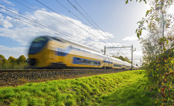 Fototapeta Passenger train moving at high speed in sunlight