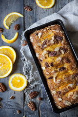 citrus plumcake with pecan walnuts on mold with orange slices