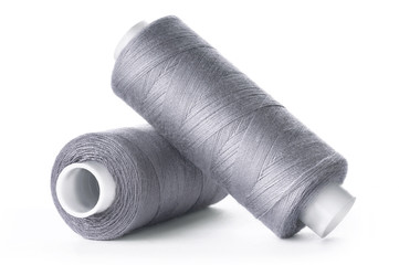 Two reels of gray thread on white background