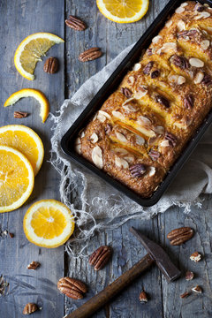 citrus plumcake with pecan walnuts on mold on table with hammer