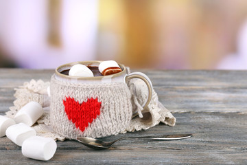 Cup of tasty hot cocoa, on wooden table, on light background