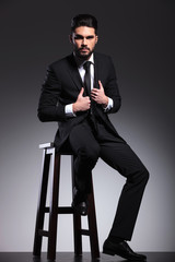 business man sitting on a stool arranging his jacket