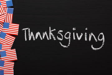 The word Thanksgiving on a blackboard with US flags
