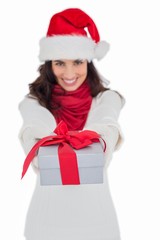 Festive brunette in santa hat giving gift