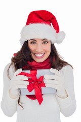 Festive brunette in santa hat holding gift