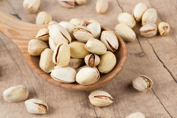 full spoon bowl of pistachio on wooden surface