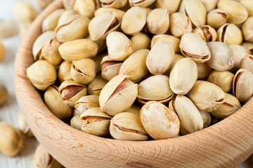 full bowl of pistachio on wooden surface