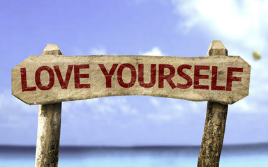 Love Yourself wooden sign with a beach on background