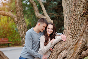 Young couple flirting in the green park. Girl holding phone goin