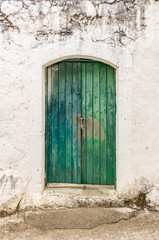 Fototapeta na wymiar Old green timber door in the scuffed wall