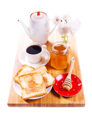 breakfast with toast bread, honey and coffee on wooden board