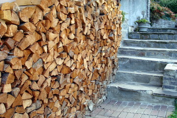Brennholz gestapelt an Treppe aus Naturstein Hauseingang