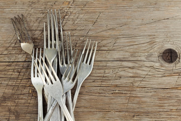 Pile of retro aluminum forks on wooden table