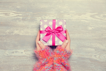 Female hands holding gift on wooden table.