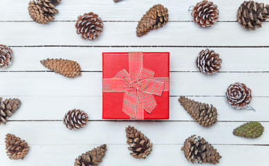 Gift box and and pine cone on a wooden table.