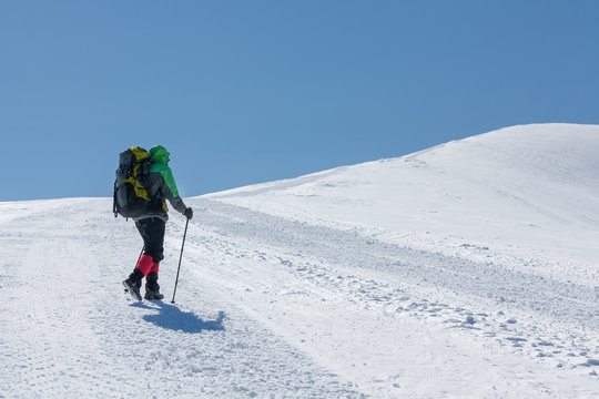 Hiker in winter mountains on sunny day