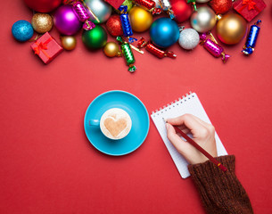 hand writing something in to the notebook near christmas toys.