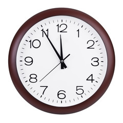 Round clock shows five minutes to twelve
