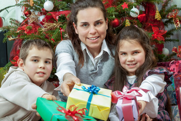 Family exchanging gifts in front of Christmas tree