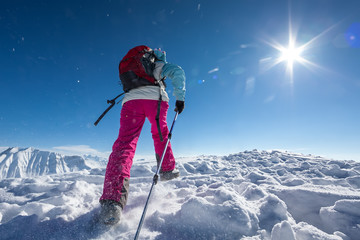 Hiker posing at top of snowy mountain during sunny day