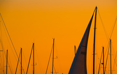 close up of a sail silhouette under an orange sky at dusk