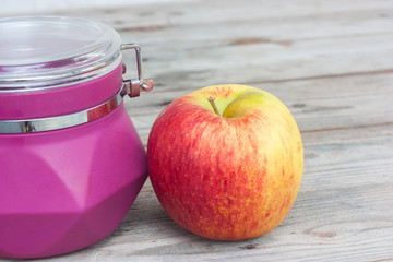 Apple and purple jar on the wooden floor.
