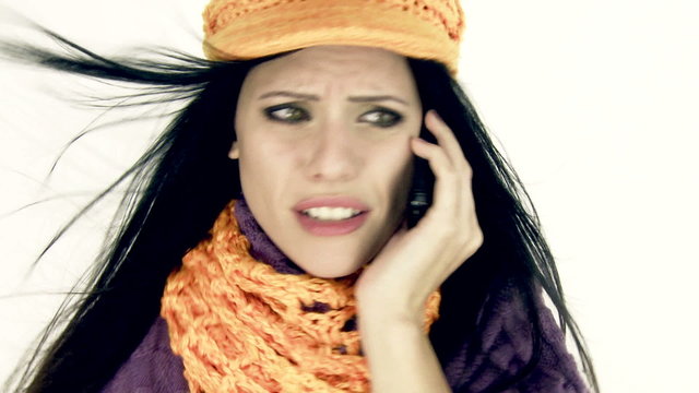 Woman talking on the phone worried with hat scarf and wind