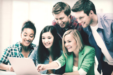smiling students looking at laptop at school