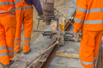 Workers in orange welding tracks