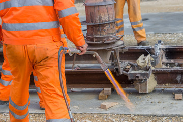 Workers in orange using an oxy fuel gas burner