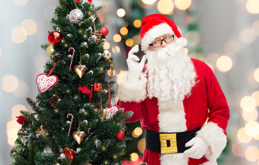 santa claus with smartphone and christmas tree