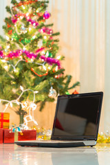 laptop with gift box and christmas lights background